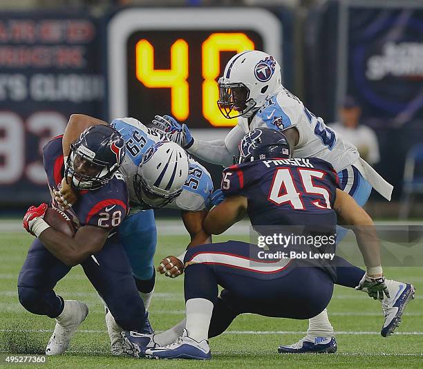 Alfred Blue of the Houston Texans is tackled by Wesley Woodyard of the Tennessee Titans as Jay Prosch looks to block Da'Norris Searcy at NRG Stadium...