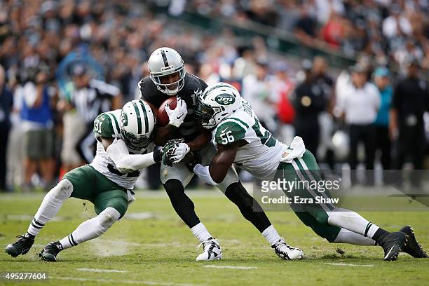 Michael Crabtree of the Oakland Raiders breaks a tackle from Demario Davis and Antonio Cromartie of the New York Jets as he runs for a 36-yard...