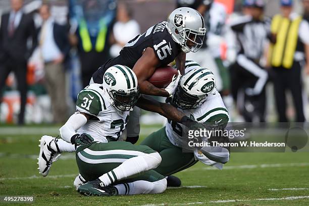 Michael Crabtree of the Oakland Raiders breaks a tackle from Demario Davis and Antonio Cromartie of the New York Jets as he runs for a 36-yard...