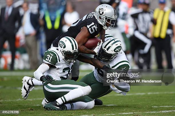 Michael Crabtree of the Oakland Raiders breaks a tackle from Demario Davis and Antonio Cromartie of the New York Jets as he runs for a 36-yard...