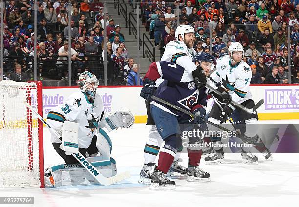 John Mitchell of the Colorado Avalanche is held by Joe Thornton of the San Jose Sharks in front of Goaltender Martin Jones at the Pepsi Center on...