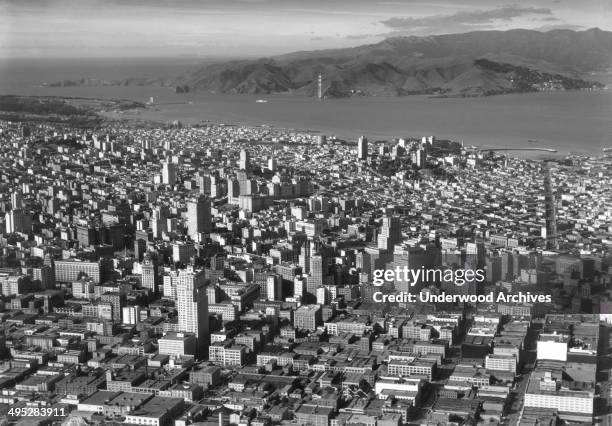 View over the downtown area and the construction of the Golden Gate Bridge in the background, San Francisco, California, 1934. The Marin Tower is...