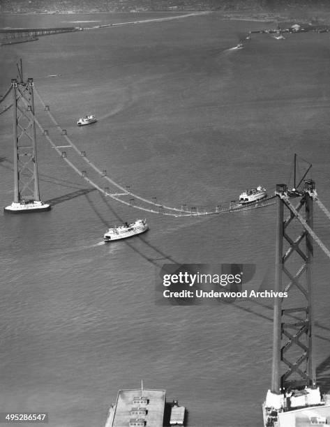 View from above of the San Francisco-Oakland Bay Bridge under construction, San Francisco, California, circa 1935. Ferry boats are seen crossing the...