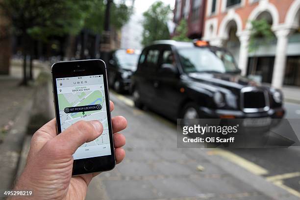 In this photo illustration, a smartphone displays the 'Uber' mobile application which allows users to hail private-hire cars from any location on...