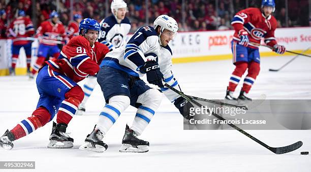 Keaton Ellerby of the Winnipeg Jets controls the puck while being challenged by Lars Eller of the Montreal Canadiens in the NHL game at the Bell...