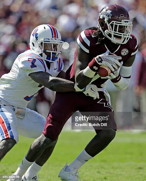 Wide receiver De'Runnya Wilson of the Mississippi State Bulldogs catches a pass as he is tackled by safety Xavier Woods of the Louisiana Tech...