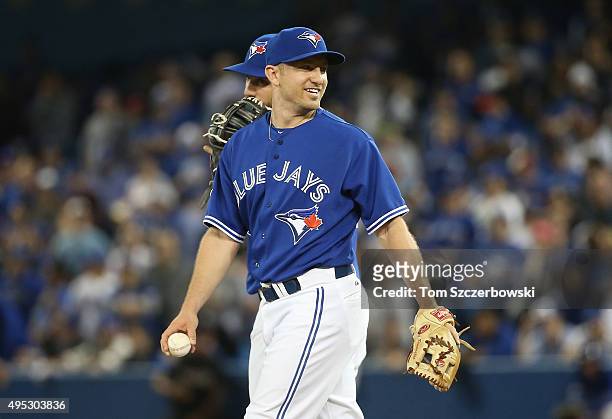 Cliff Pennington of the Toronto Blue Jays smiles while pitching in the ninth inning against the Kansas City Royals during game four of the American...