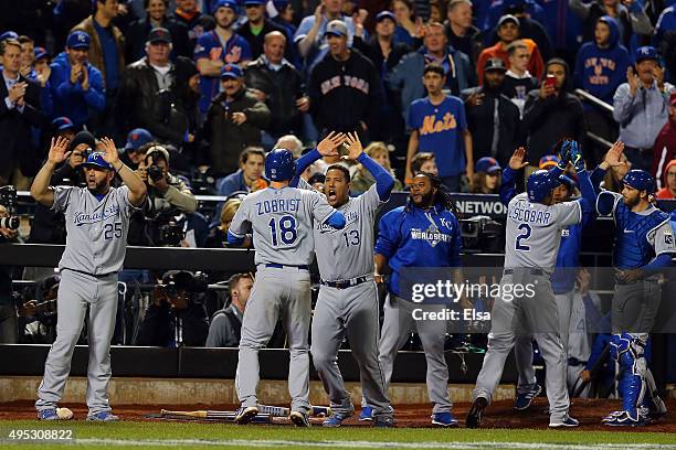 Ben Zobrist of the Kansas City Royals celebrates with his teammates after scoring a run off of a three run RBI double hit by Lorenzo Cain to also...