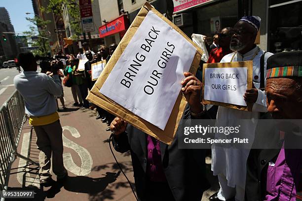 People hold up signs as local clergy, activists and and community leaders protest for the safe return of the 276 abducted schoolgirls outside the...