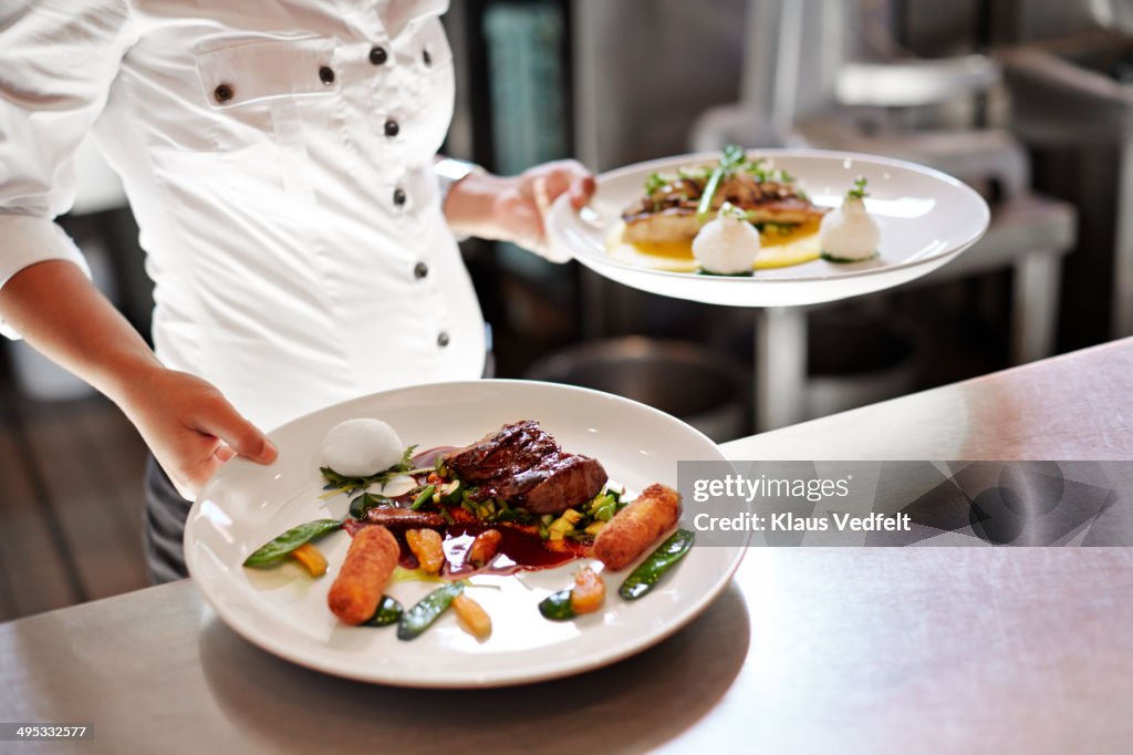 Waiter picking up dishes in kitchen at restaurant