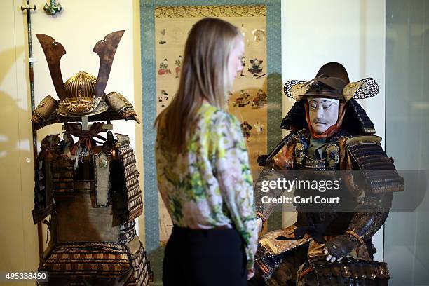 Member of staff poses next to a figure of a samurai dressed in armour dating from around 1800 during a press preview for the Victoria and Albert...