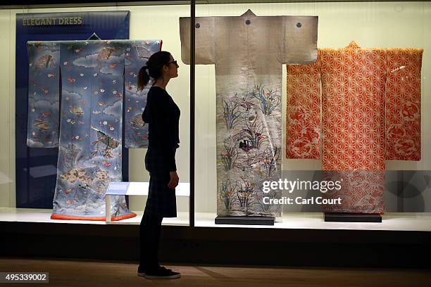 Member of staff poses next to an outer kimono , a summer kimono and a kimono for a young girl during a press preview for the Victoria and Albert...