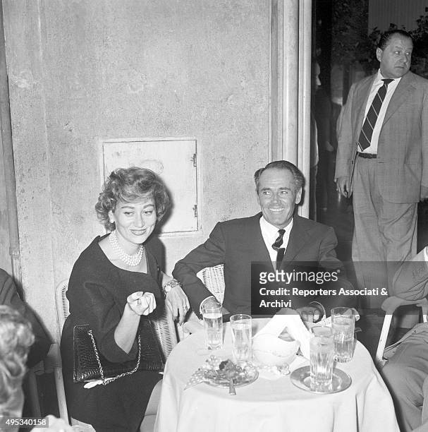 American actor Henry Fonda smiling seated at a table at Casina delle Rose of Via Veneto beside his wife Afdera Franchetti. Rome, 18th September 1958