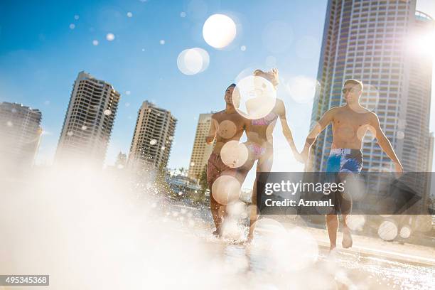 friends running into the sea - gold coast australia beach stock pictures, royalty-free photos & images