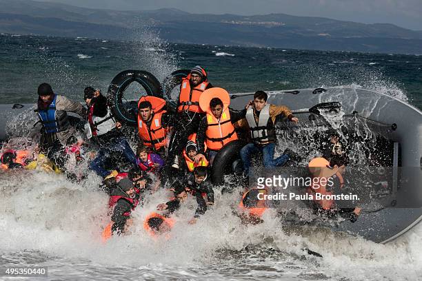 Refugees arriving to the island of Lesbos fall out of a boat as it capsizes on landing in rough seas coming from Turkey on October 31, 2015 in...