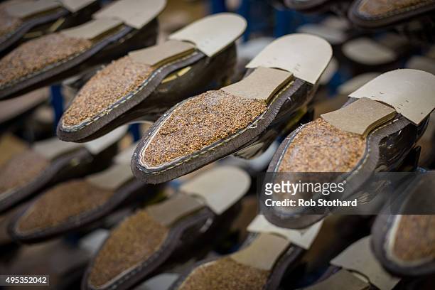 The soles of unfinished shoes are seen on racks inside the Joseph Cheaney and Sons factory on August 25, 2015 in Desborough, United Kingdom. J....