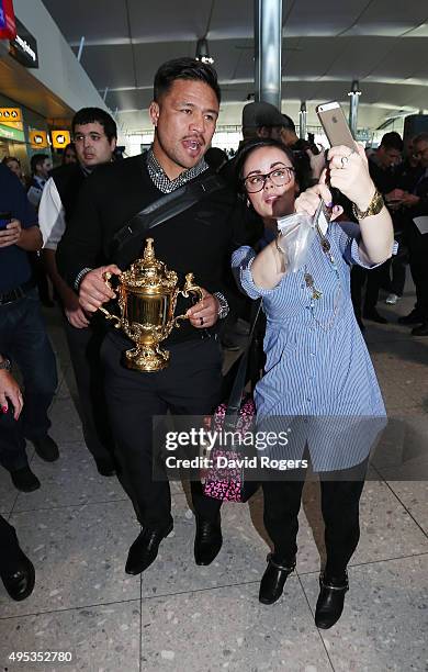 Keven Mealamu, of Rugby World Cup winners, the New Zealand All Blacks, poses with a supporter as he holds the Webb Ellis Cup as the team arrive at...