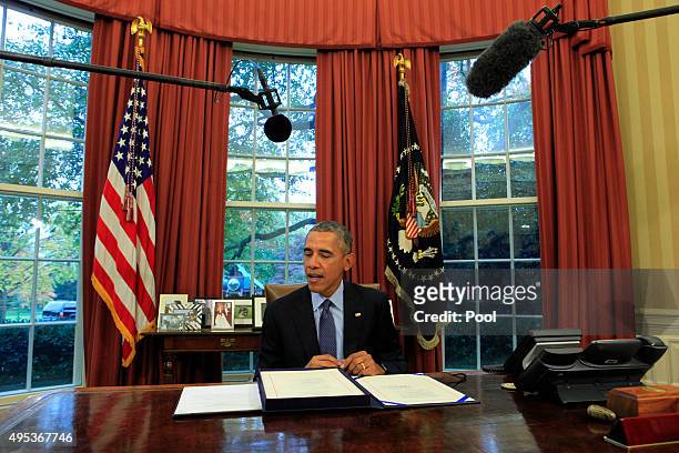 President Barack Obam alooks at the bipartisan budget bill 2015 as he speaks to the media before he signs the bill into lawin the Oval Office of the...