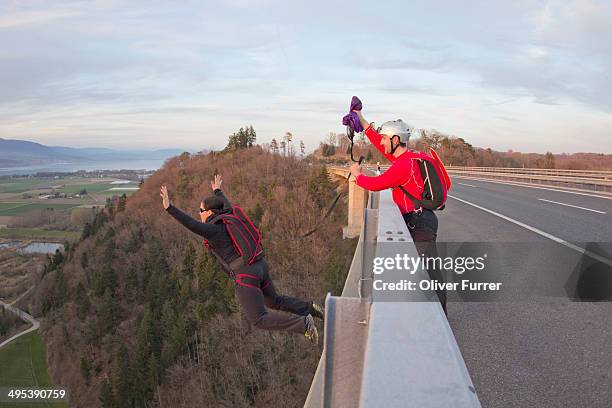 girl jumping from a bridge with assistance - hang parachute stock-fotos und bilder