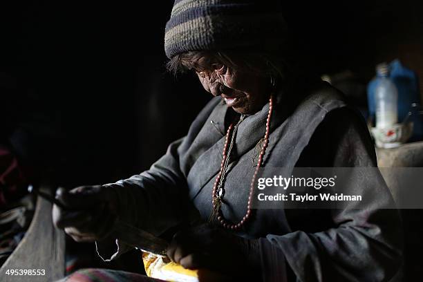 Pema Dolma opens a butter package to make a prayer candle in her cliffside home on May 23, 2014 in Chosher, Nepal. Humans have lived in caves carved...