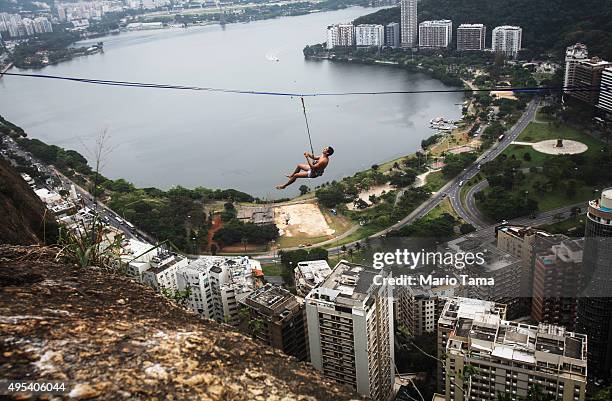 Participant hangs on a slackline set up between rocks in the Cantagalo favela community during the Highgirls Brasil festival on November 2, 2015 in...