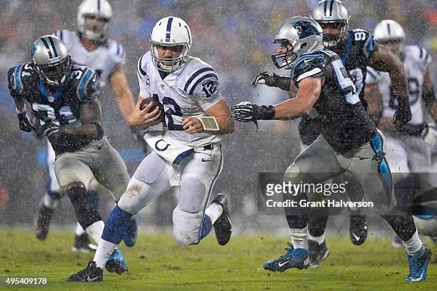 Andrew Luck of the Indianapolis Colts scrambles as Luke Kuechly of the Carolina Panthers pursues during their game at Bank of America Stadium on...