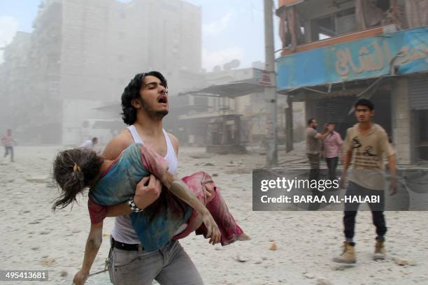 Man carries a young girl who was injured in a reported barrel-bomb attack by government forces on June 3, 2014 in Kallaseh district in the northern...