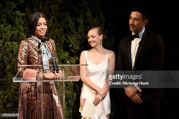 Designer and winner Aurora James accepts an award onstage with Actress Amanda Seyfried and designer and keynote speaker Riccardo Tisci at the 12th...