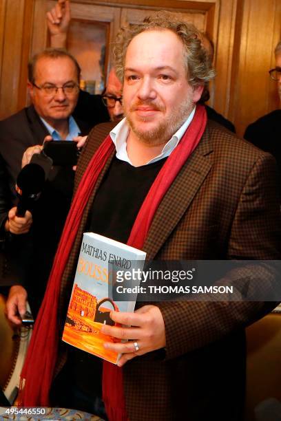 French author Mathias Enard poses with his book "Boussole" at the Drouant restaurant in Paris after he was awarded with France's top literary prize,...
