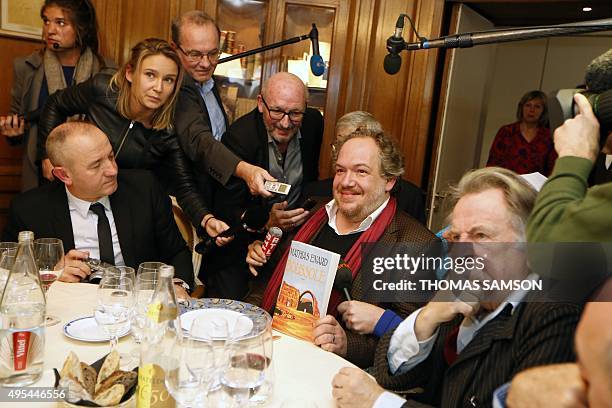 French author Mathias Enard poses with his book "Boussole" next to members of the Goncourt Academie and French authors Philippe Claudel and Regis...