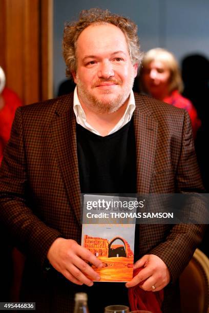 French author Mathias Enard poses with his book "Boussole" at the Drouant restaurant in Paris after he was awarded with France's top literary prize,...