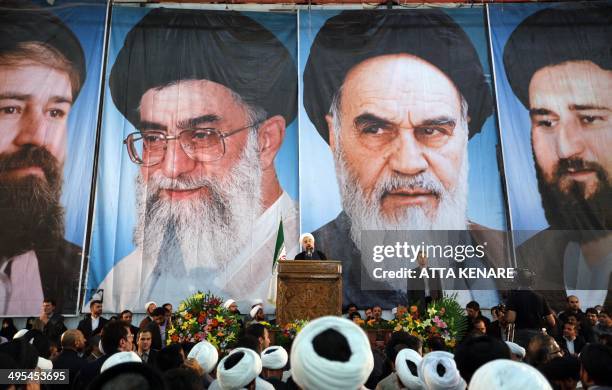Iranian President Hassan Rouhani delivers a speech under portraits of Iran's supreme leader, Ayatollah Ali Khamenei and Iran's founder of the Islamic...