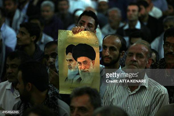 An Iranian man holds a photo showing Iran's supreme leader Ayatollah Ali Khamenei, and Iran's late Ayatollah Ruhollah Khomeini, while listening to...