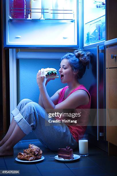 woman eating unhealthy midnight snack late night under open refrigerator - caught in the act stock pictures, royalty-free photos & images