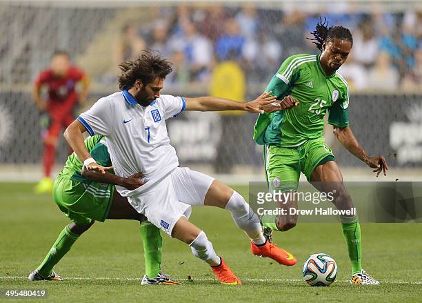 Giorgos Samaras of Greece gets pulled down by Kunle Odunlami of Nigeria, as Odunlami's teammate Michael Uchebo tries to gain control of the ball...