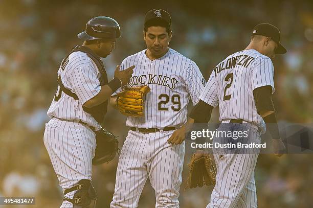 Wilin Rosario of the Colorado Rockies and Troy Tulowitzki visit with Jorge De La Rosa on the mound after De La Rosa gave up back-to-back home runs in...