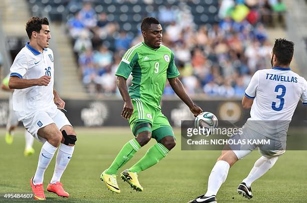 Nigerian national team striker Emmanuel Emenike controls the ball between Greek defender Giorgos Tzavellas and midfielder Lazaros Chritodoulopoulos...