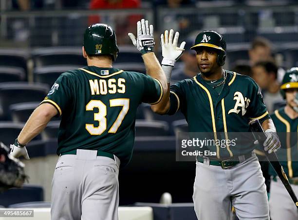 Brandon Moss of the Oakland Athletics is congratulated by teammate Yoenis Cespedes after Moss hit a solo home run in the 10th inning against the New...