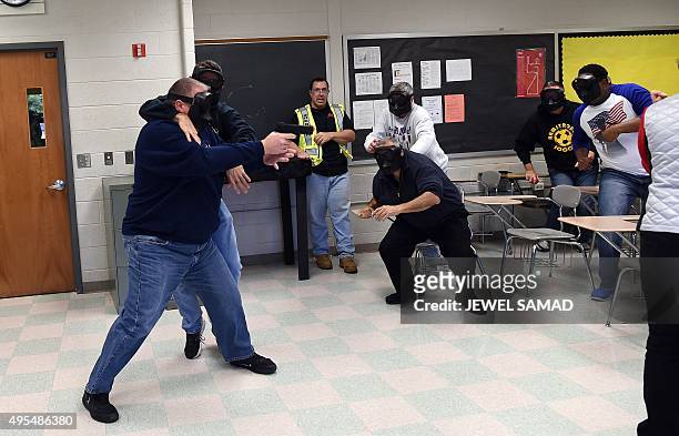 An "active shooter" is grabbed as he enters a classroom as "students" take cover during ALICE training at the Harry S. Truman High School in...