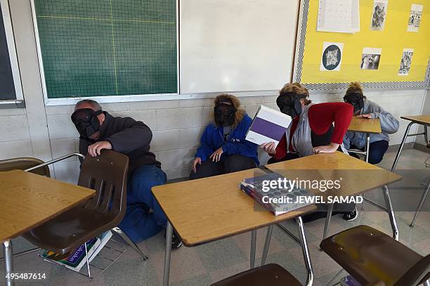 Participants hide from an "active shooter" during ALICE training at the Harry S Truman High School in Levittown, Pennsylvania, on November 3, 2015....