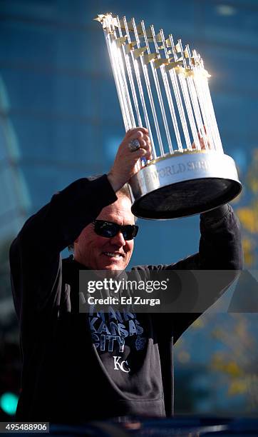 Ned Yost manager of the Kansas City Royals holds up the championship trophy as he makes his way through the streets during a parade to celebrate...