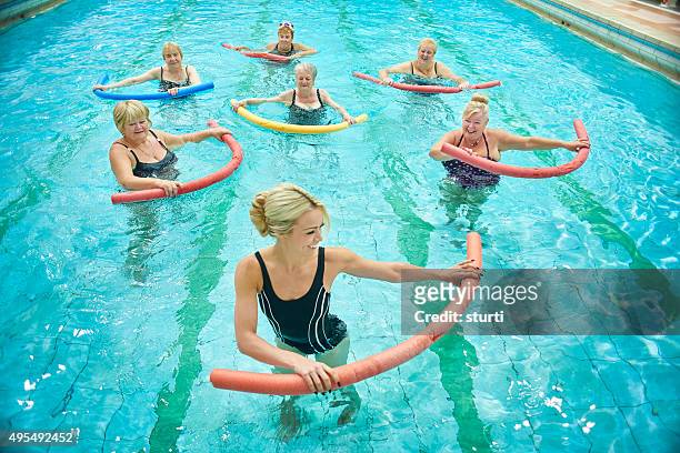 senior women led by female instructor at water aerobics - aquarobics stock pictures, royalty-free photos & images