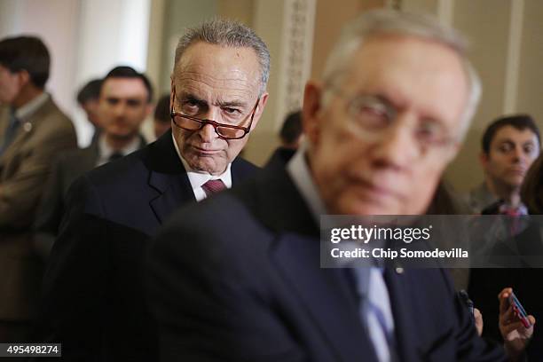 Sen. Charles Schumer look sover the shoulder of Senate Majority Leader Harry Reid as he talks to reporters following the weekly Senate Democratic...