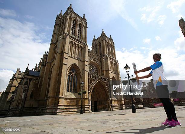 In this handout image provided by Glasgow 2014 Ltd, Baton bearer Rondene Vassell holds the Queen's Baton in front of Bristol Cathedral as the Glasgow...