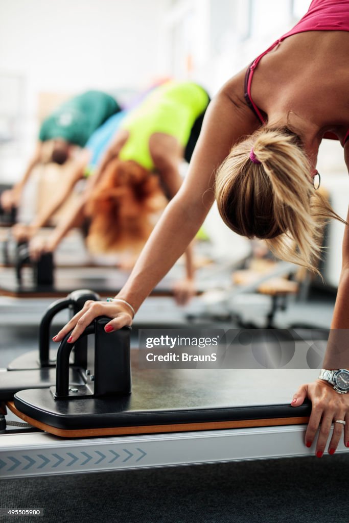 Group of people having a Pilates class on exercise machines.