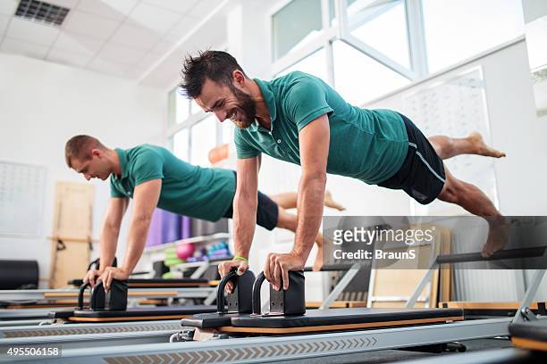 zwei junge männer mit einem pilates-kurs im fitness-club. - pilates gerät stock-fotos und bilder