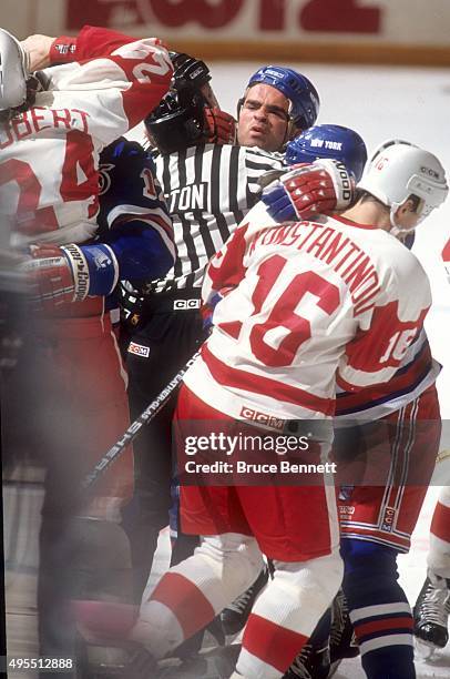 Tie Domi of the New York Rangers is held back by linesman Randy Mitton as Domi tries to get at Bob Probert of the Detroit Red Wings on February 9,...