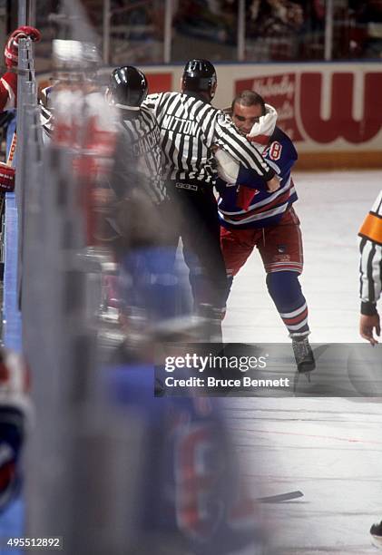 Tie Domi of the New York Rangers is held back by linesman Randy Mitton as Domi tries to get at Bob Probert of the Detroit Red Wings on February 9,...