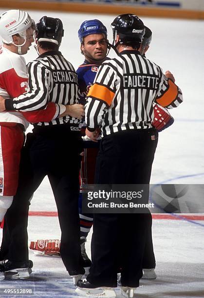 Tie Domi of the New York Rangers is held back by linesman Randy Mitton as referee Mark Faucette talks to Domi during an NHL game against the Detroit...