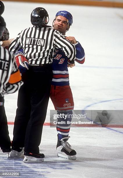 Tie Domi of the New York Rangers is held back by linesman Randy Mitton during an NHL game against the Detroit Red Wings on February 9, 1992 at the...